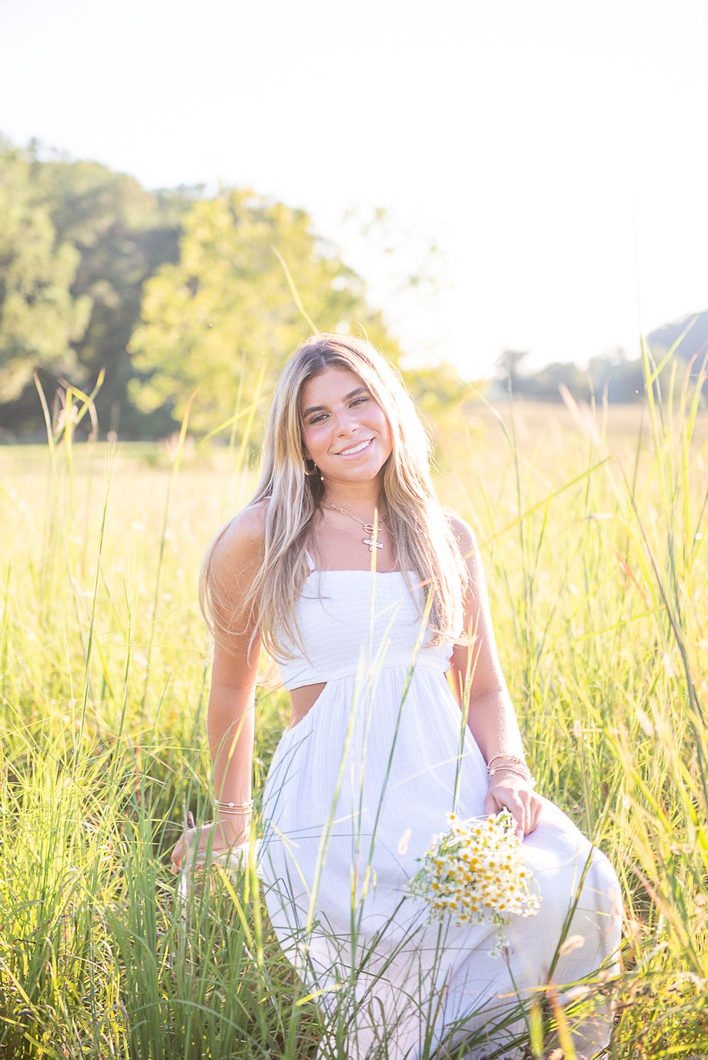 Portrait series of person in flowing white dress posing with wildflowers in sun-drenched meadow.