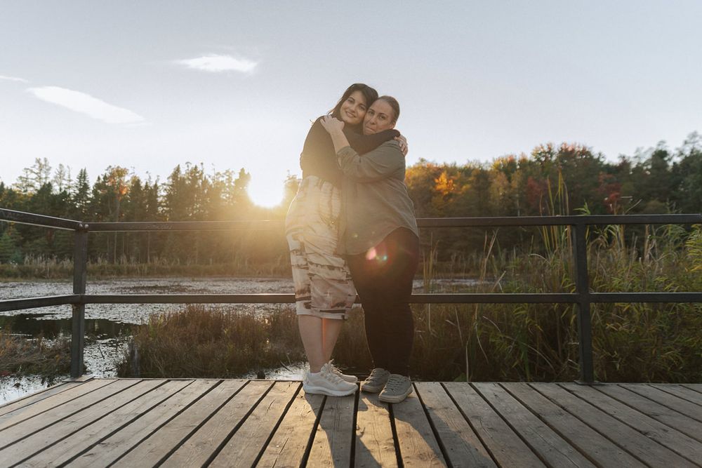 Romantic sunset silhouettes on a wooden dock overlooking a serene lake.