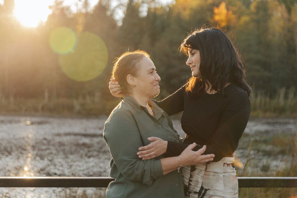 Two people share an intimate moment in a golden sunlit field during sunset with lens flare effects.