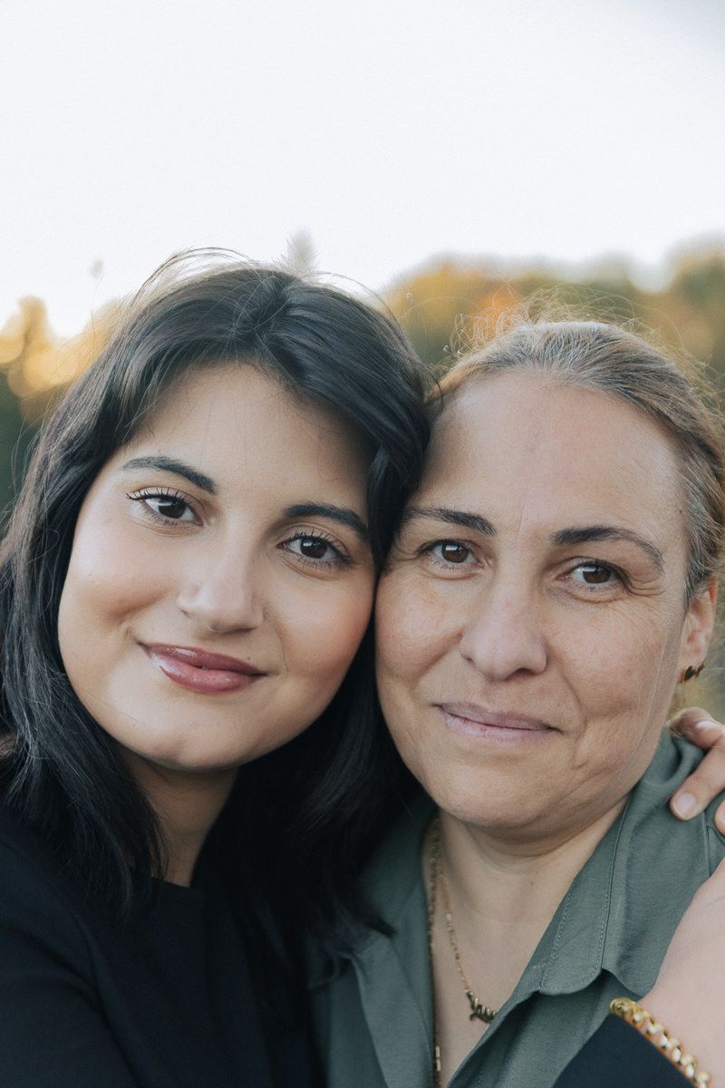 Close up portrait of two people smiling at camera with warm autumn background colors.