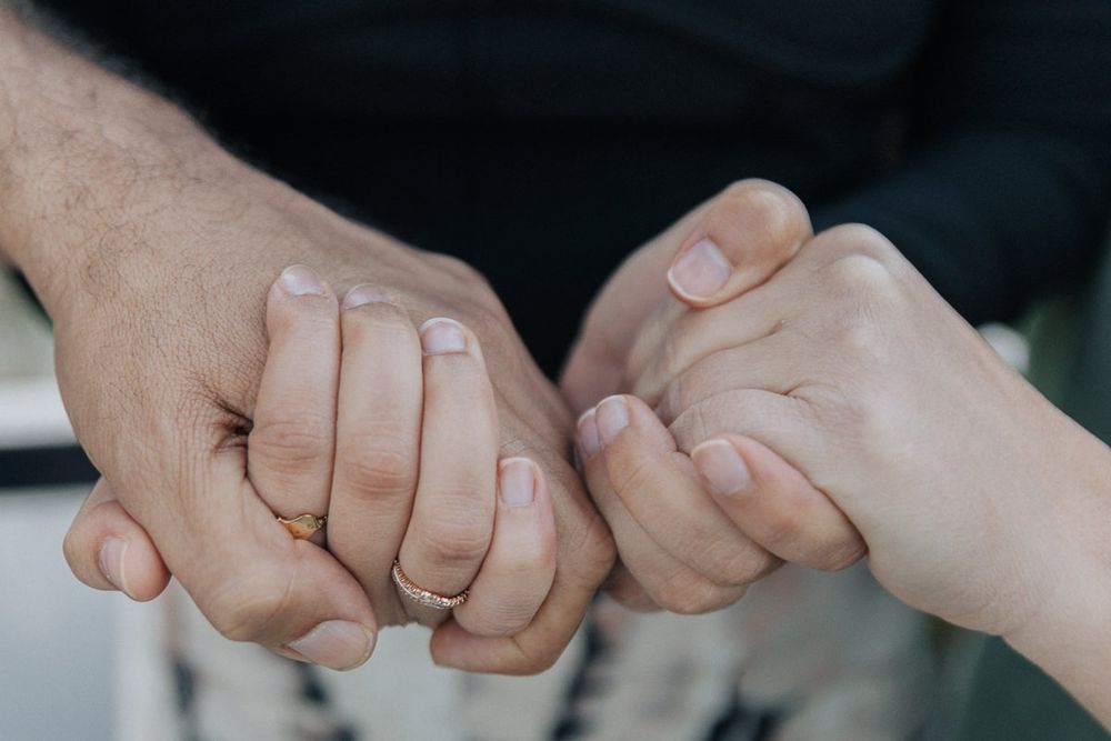 A close-up view of hands joined together in unity against a dark background.