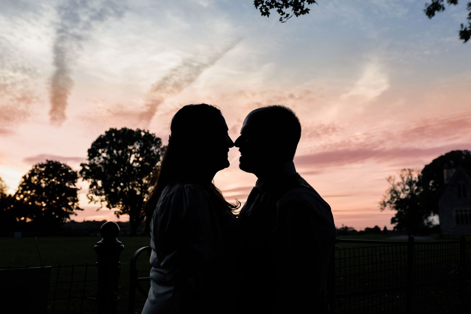 A joyful couple holds hands while walking through a grassy field on their wedding day.