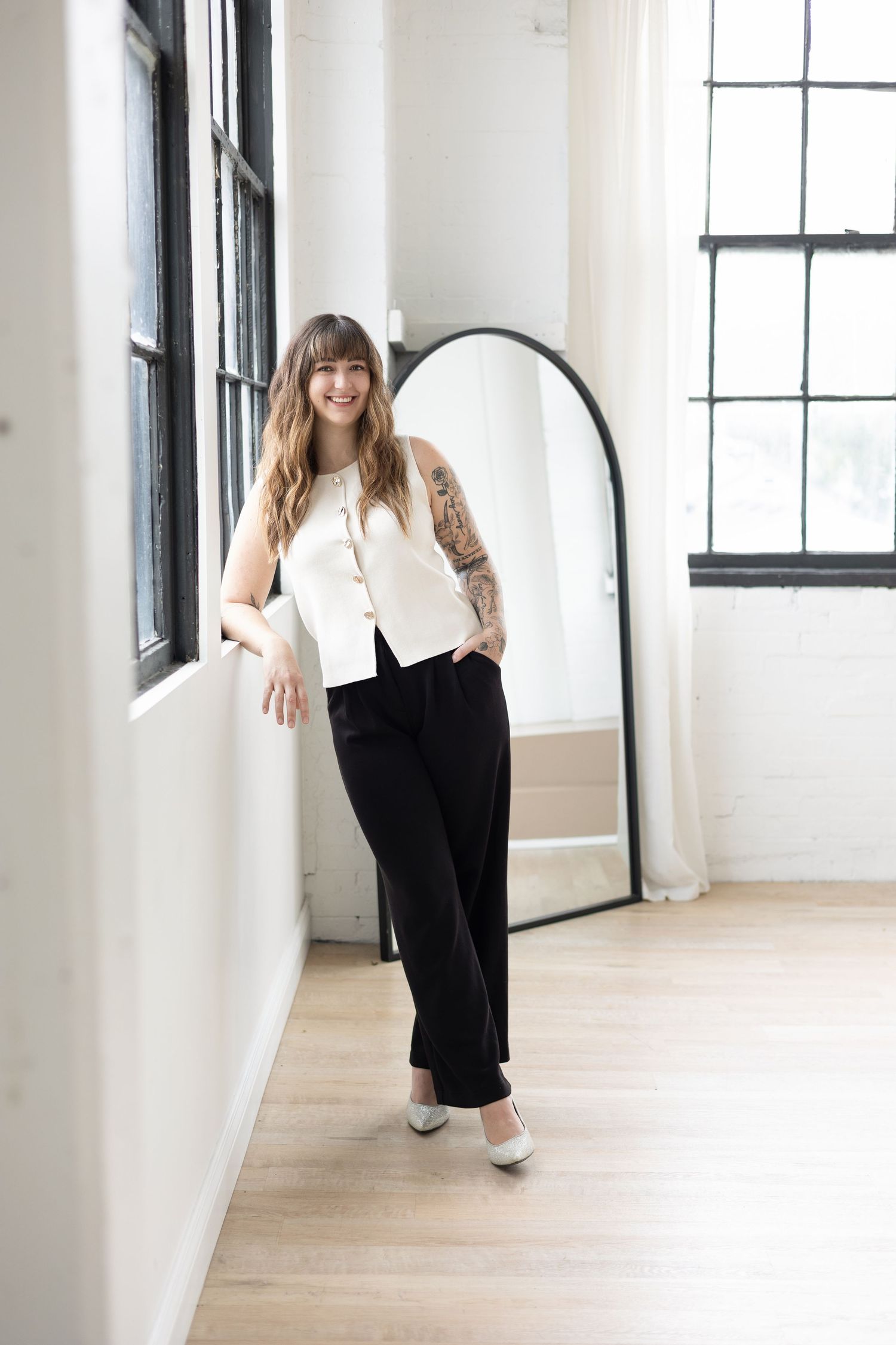 Nurse injector in powerhouse pose during branding photoshoot with white short sleeve top, black dress pants, and heels at Parkhill Studios