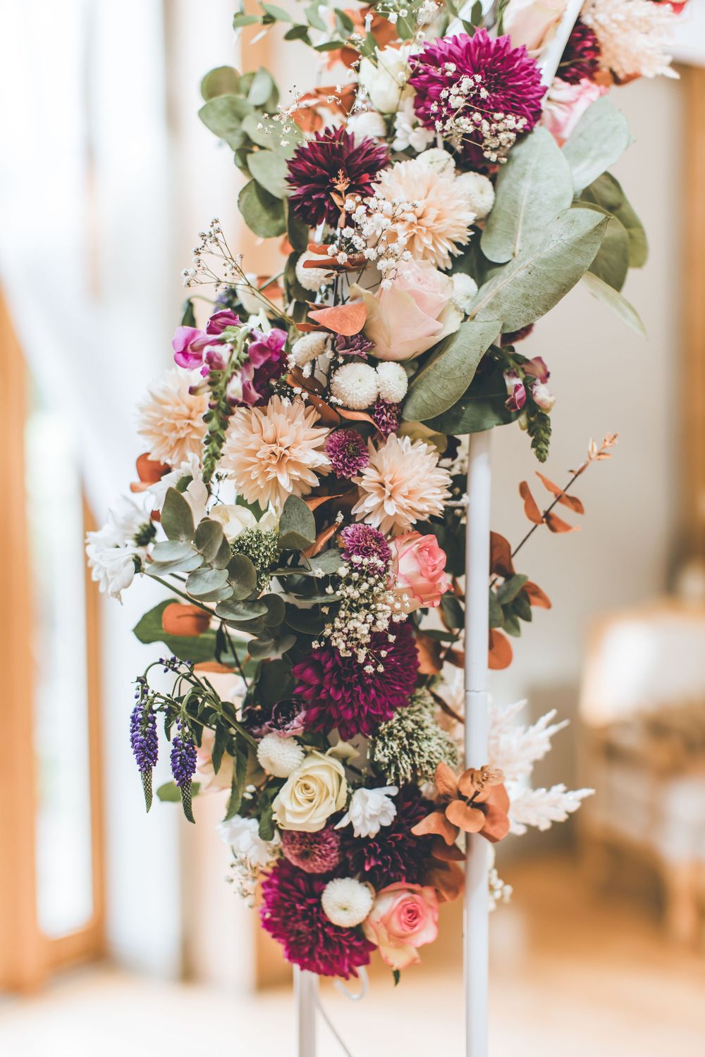 Vibrant floral wedding arrangement featuring pink, purple and white blooms with eucalyptus against a light background.