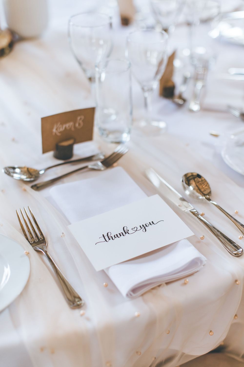 Elegant place settings with handwritten name cards on crisp white linens at a formal dining table.