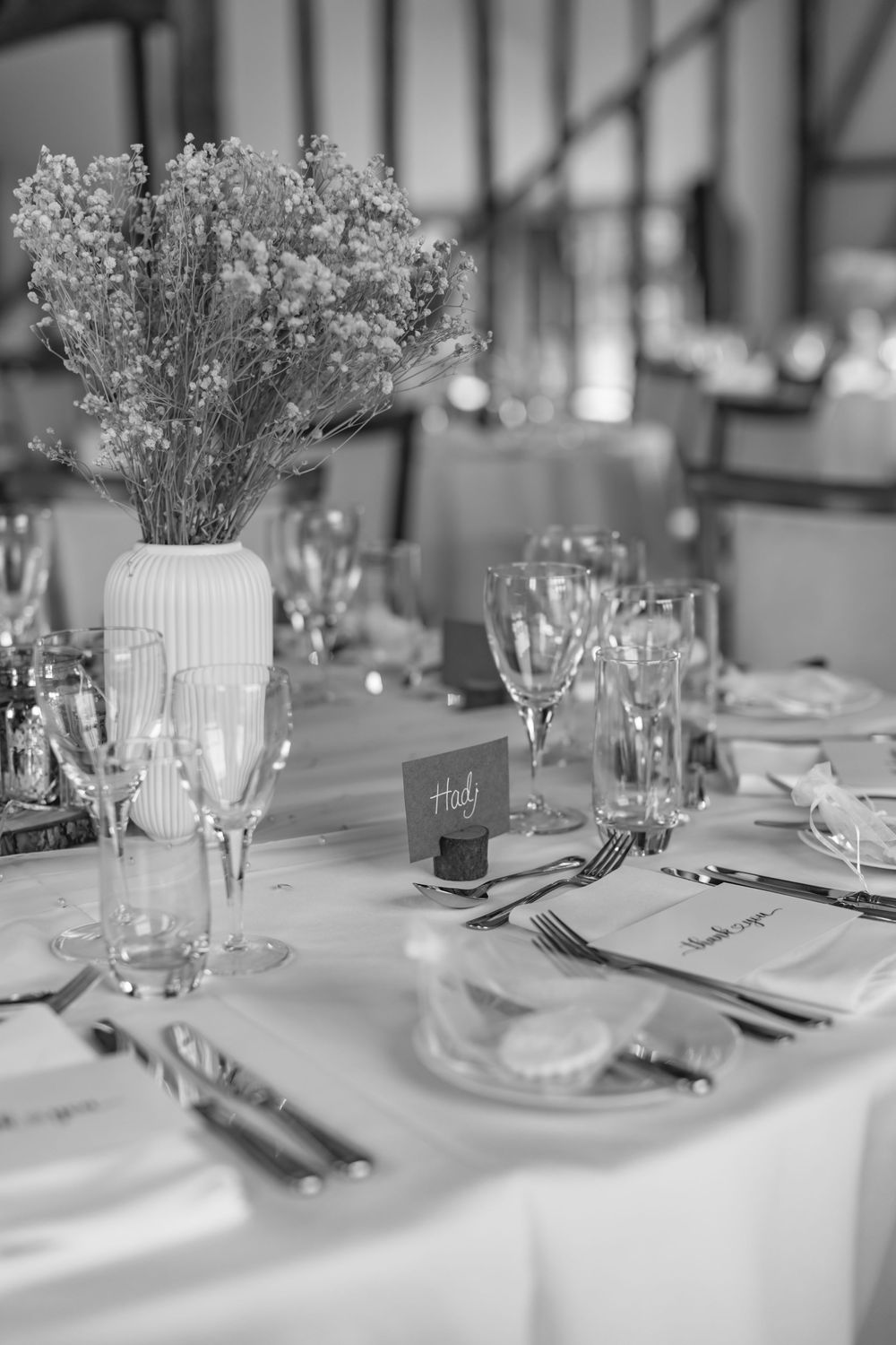 Elegant wedding reception table setting with white linens and delicate floral centerpieces.
