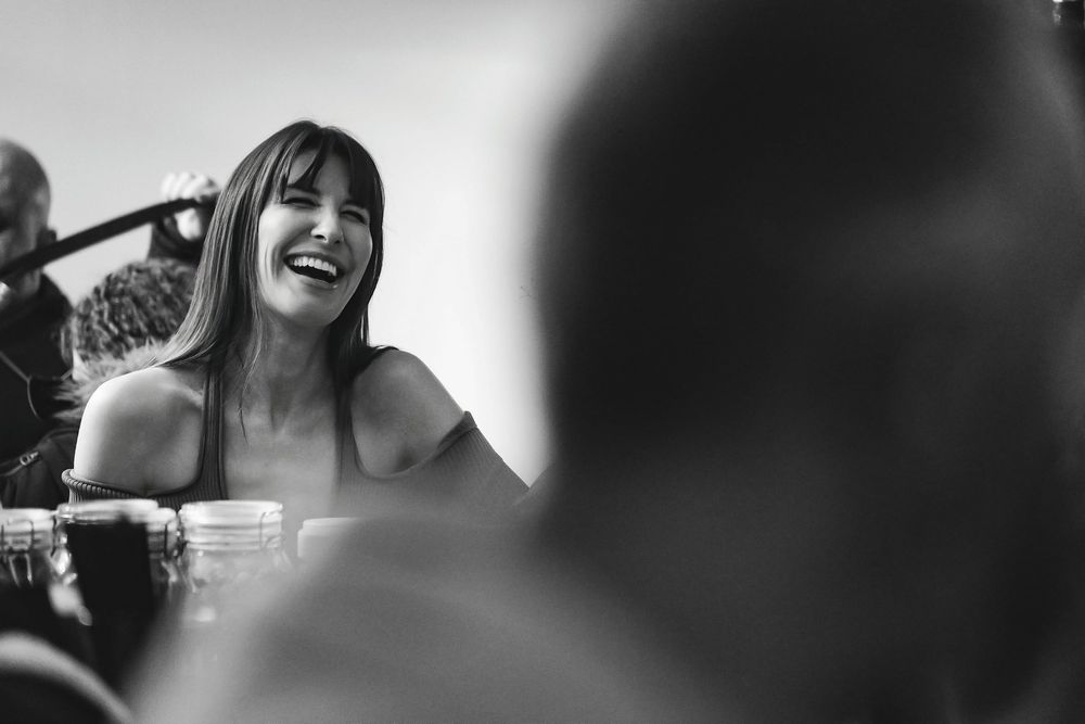 Black and white photo of a woman laughing joyfully at an outdoor social event.
