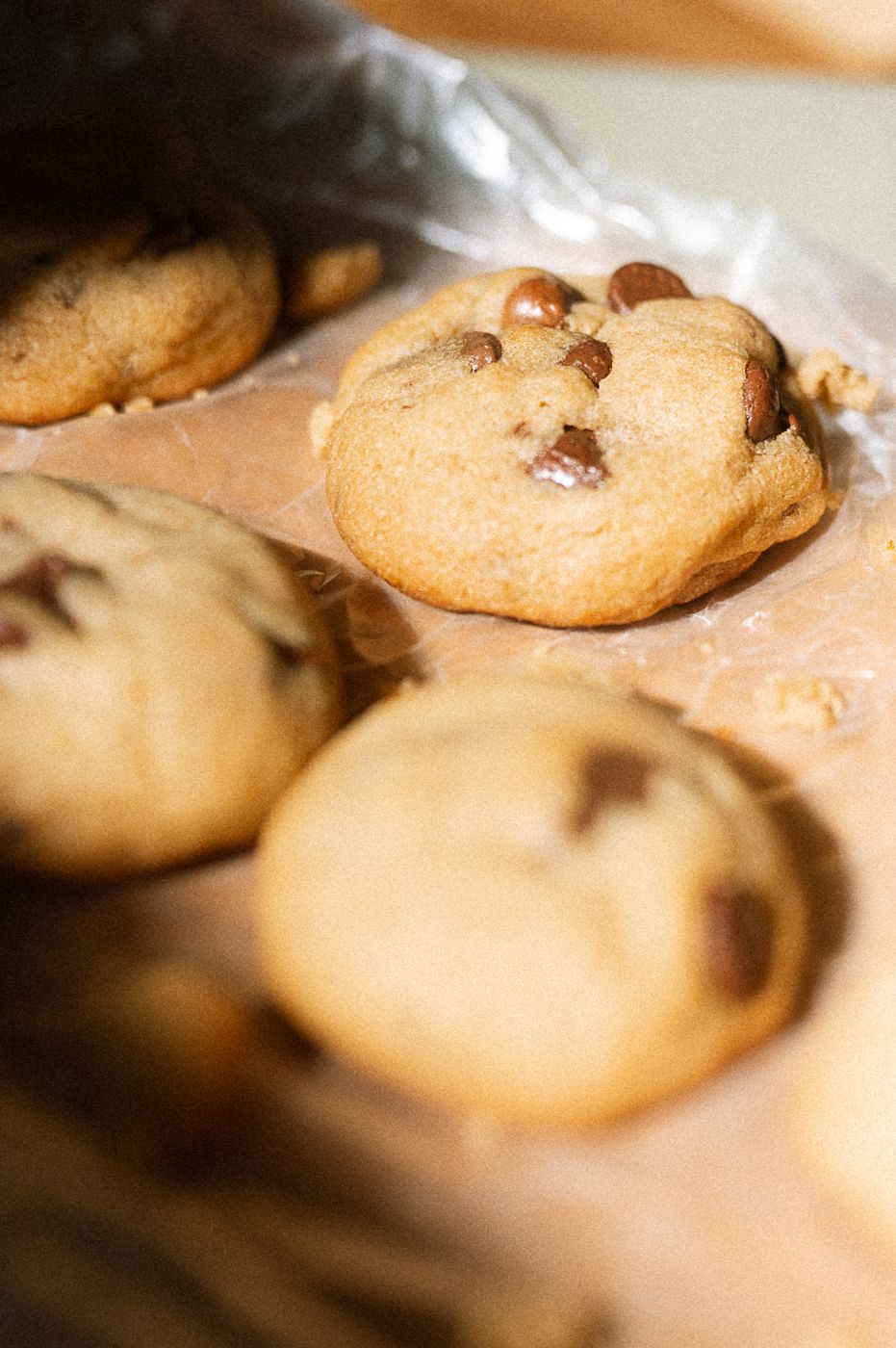 Freshly baked chocolate chip cookies arranged in a row showing varying levels of focus and texture.