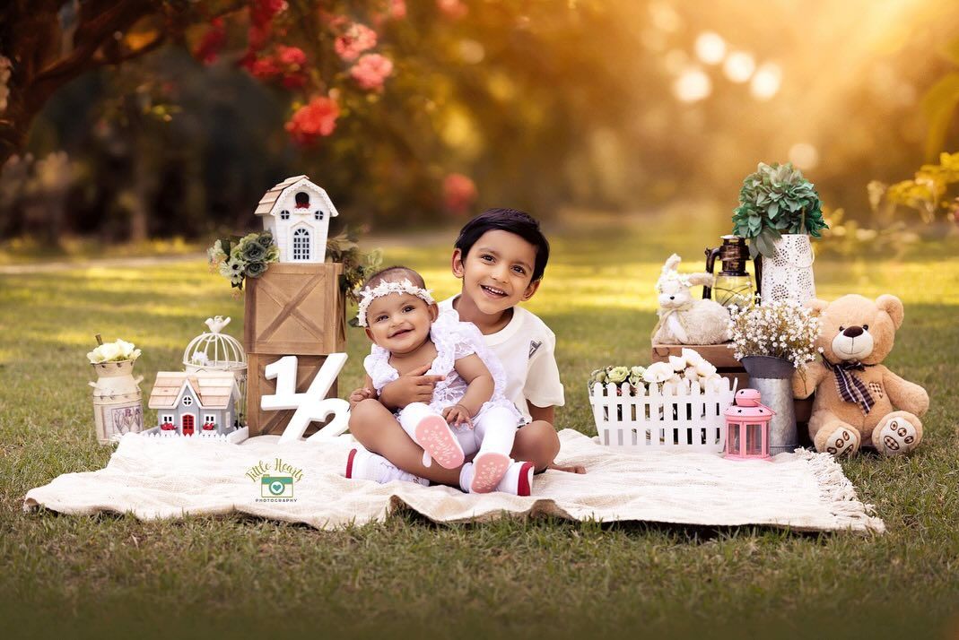 Children enjoying a charming outdoor picnic setup with teddy bears and decorative items on a blanket at sunset.