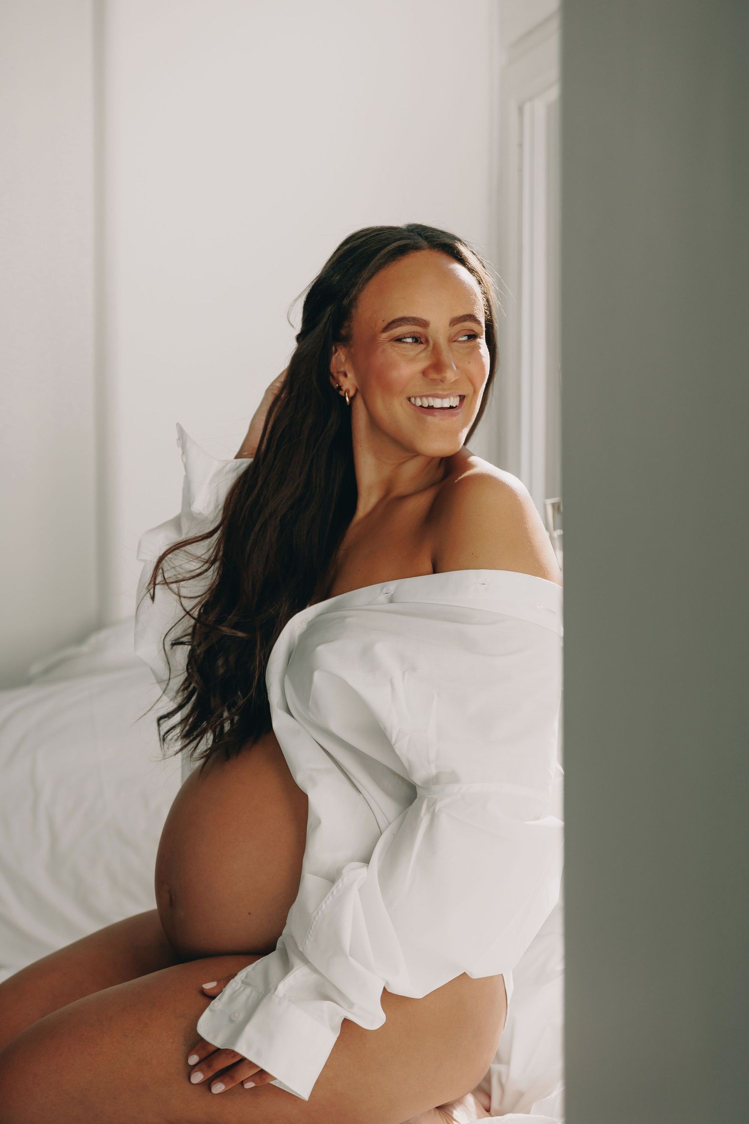 Gravid kvinna ler stort under porträttfotografering på hotellrum
