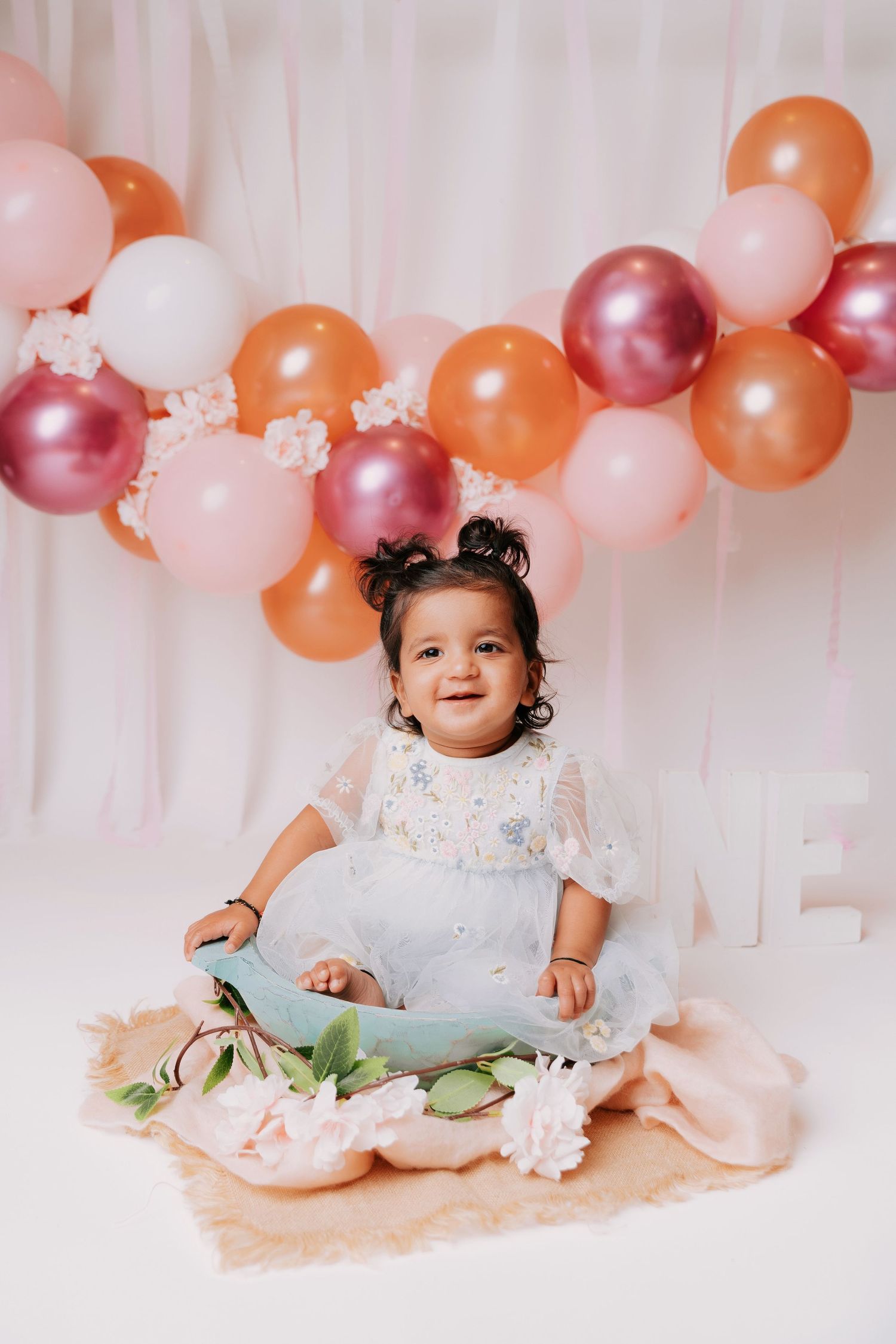 Baby's cake smash photography session with pink and orange balloon backdrop.