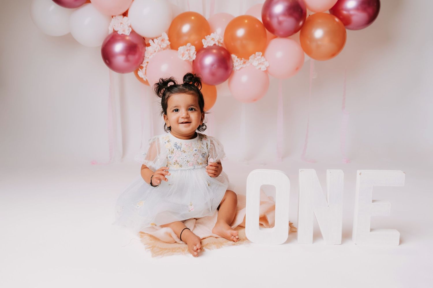 First birthday celebration setup with ONE text and festive balloon arch.