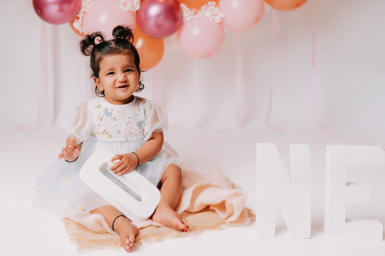 First birthday photoshoot with baby and decorative balloon arrangement.