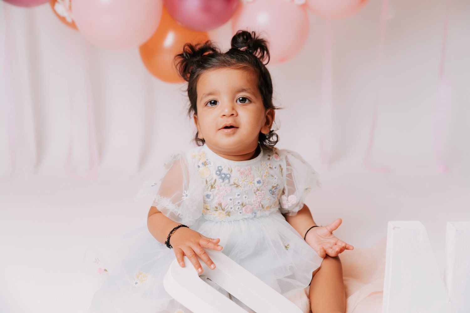 Baby's first birthday portrait session with festive balloon decorations.