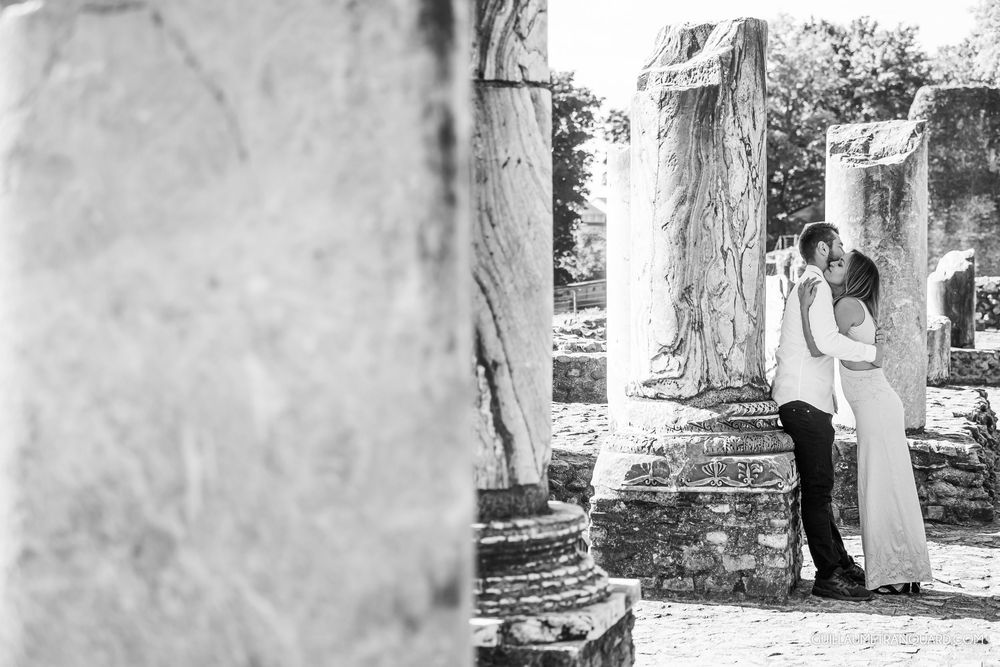 Monochrome engagement session features loving couple against textured stone backdrop.