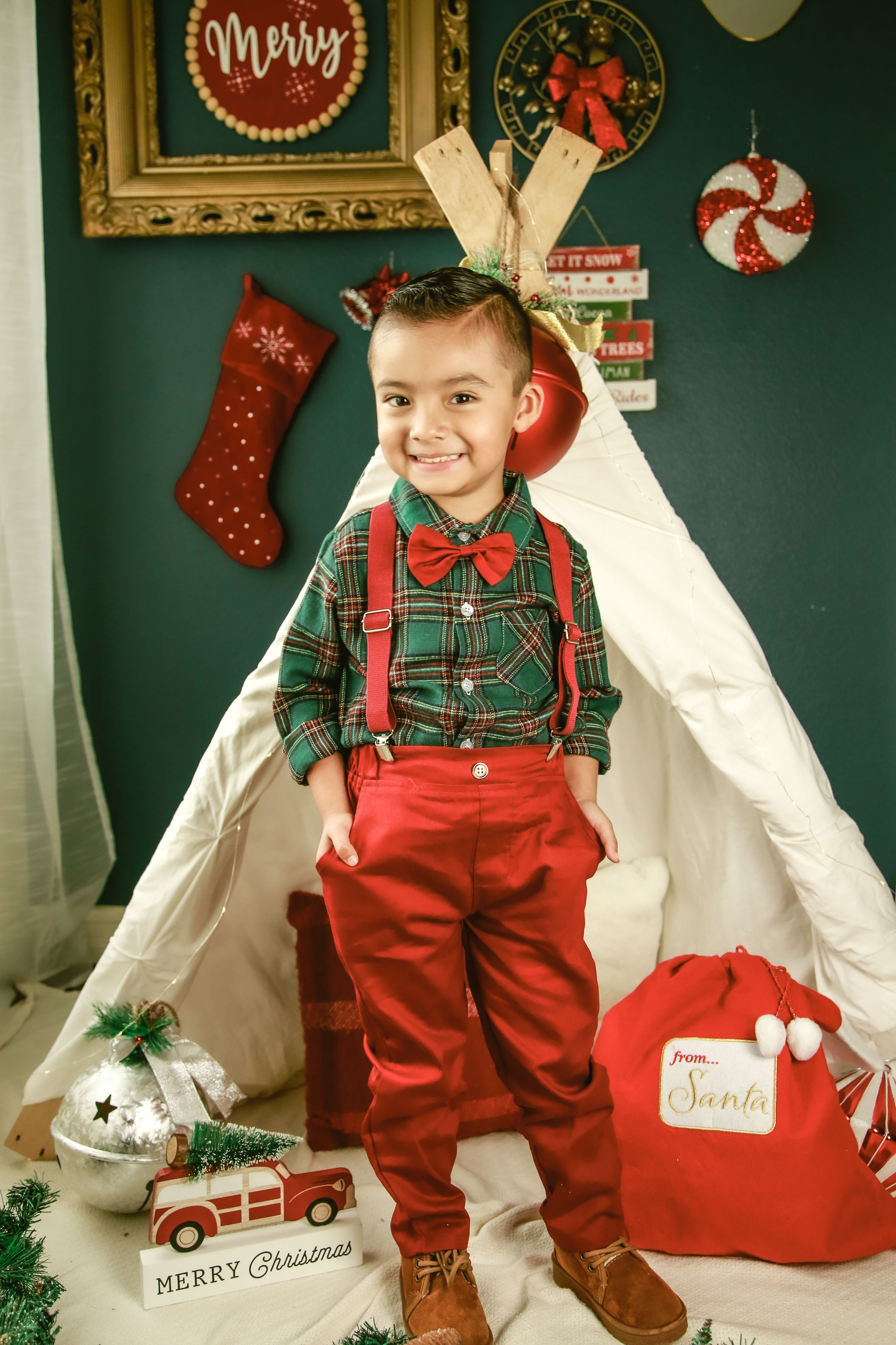 Christmas themed photo setup with teepee tent and festive red and green decorations.