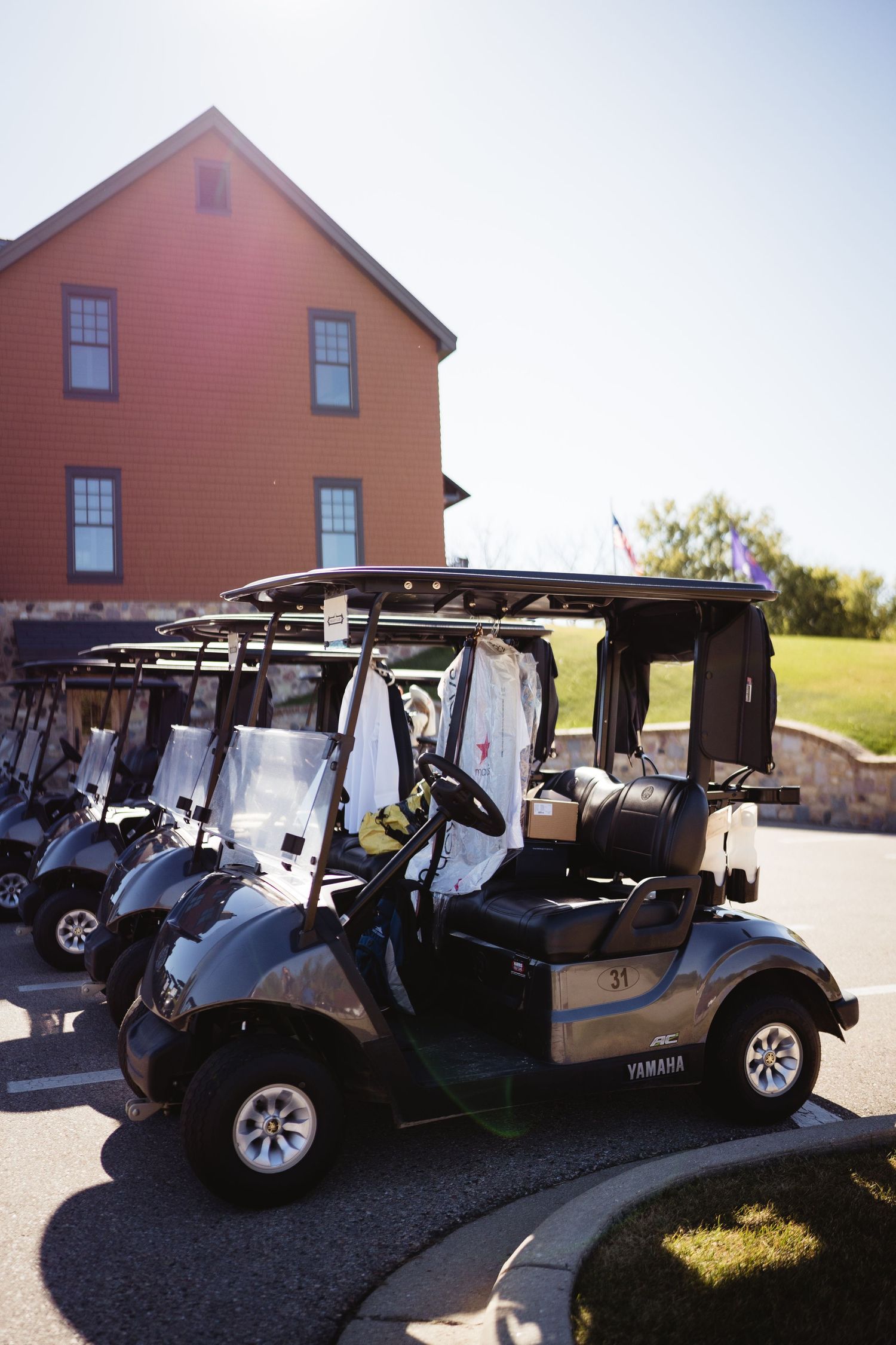 Row of golf carts parked outside an orange historic building on a sunny day.