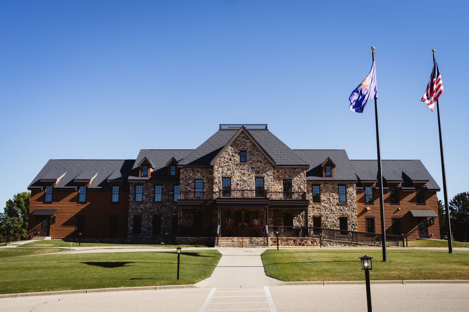 Exterior view of a large brick building complex with multiple wings and American flags flying out front.