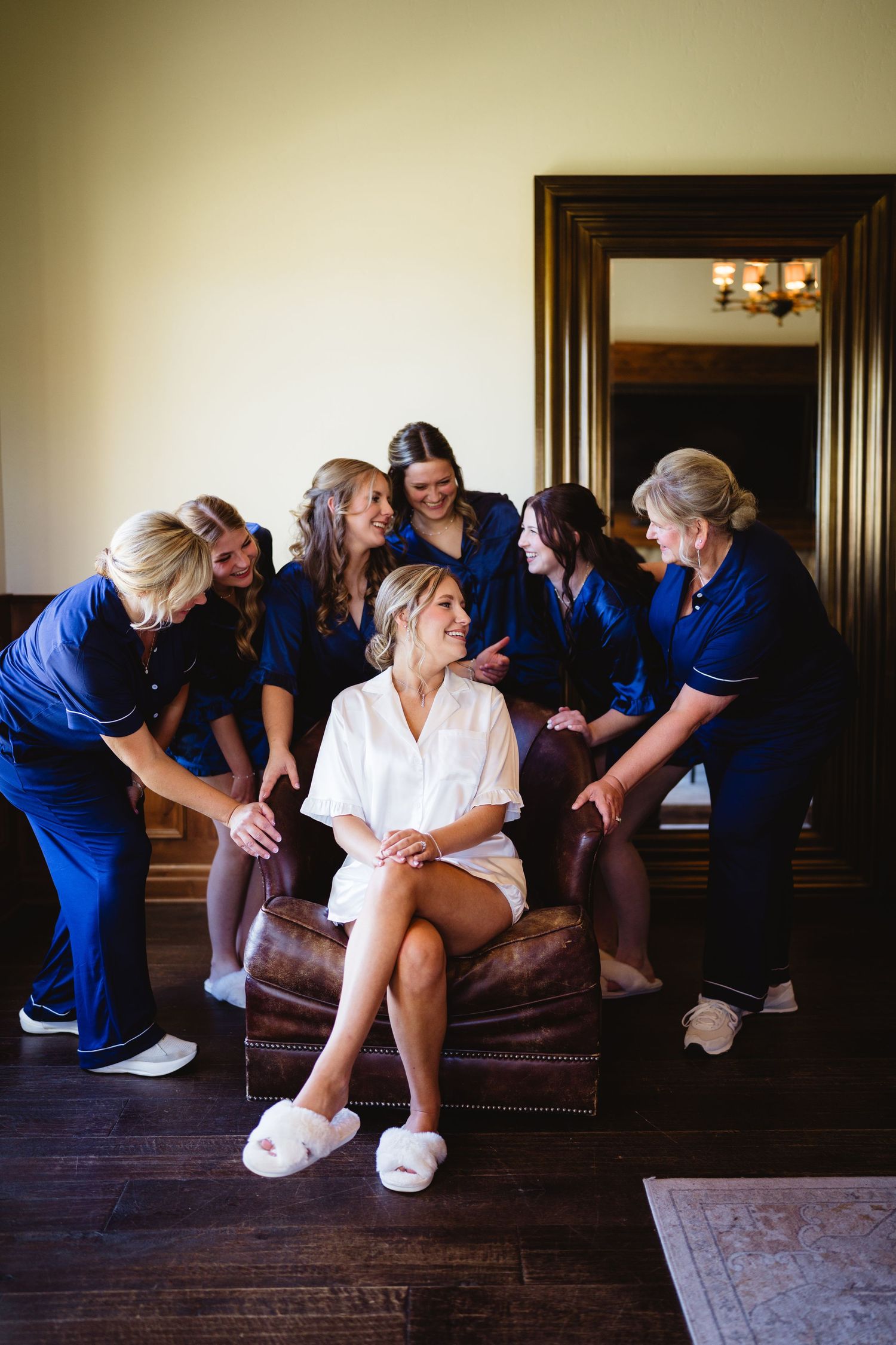 Group of people in blue uniforms and white sneakers gathered on a brown leather couch in a dimly lit room.