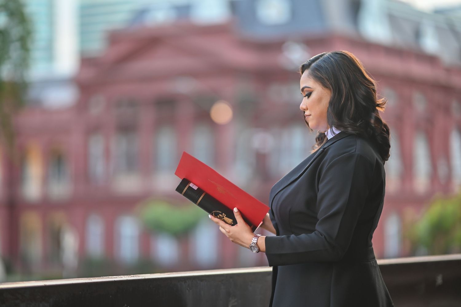 Professional figure reading a red book with historic architecture in background.