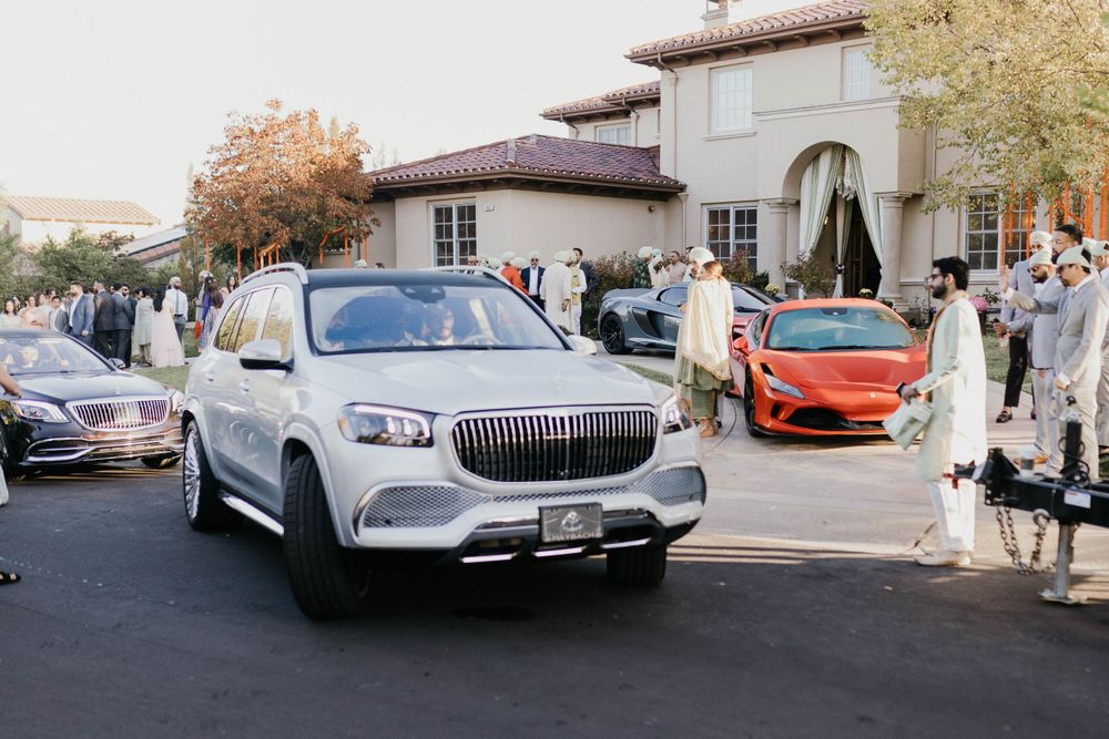 Luxury cars lined up outside a wedding venue including vintage and modern high-end vehicles.