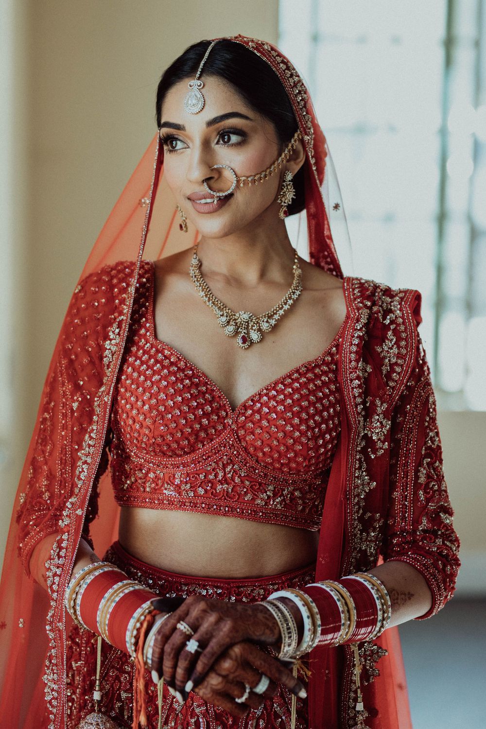 Traditional Indian bridal attire featuring red lehenga with intricate embroidery and matching jewelry.