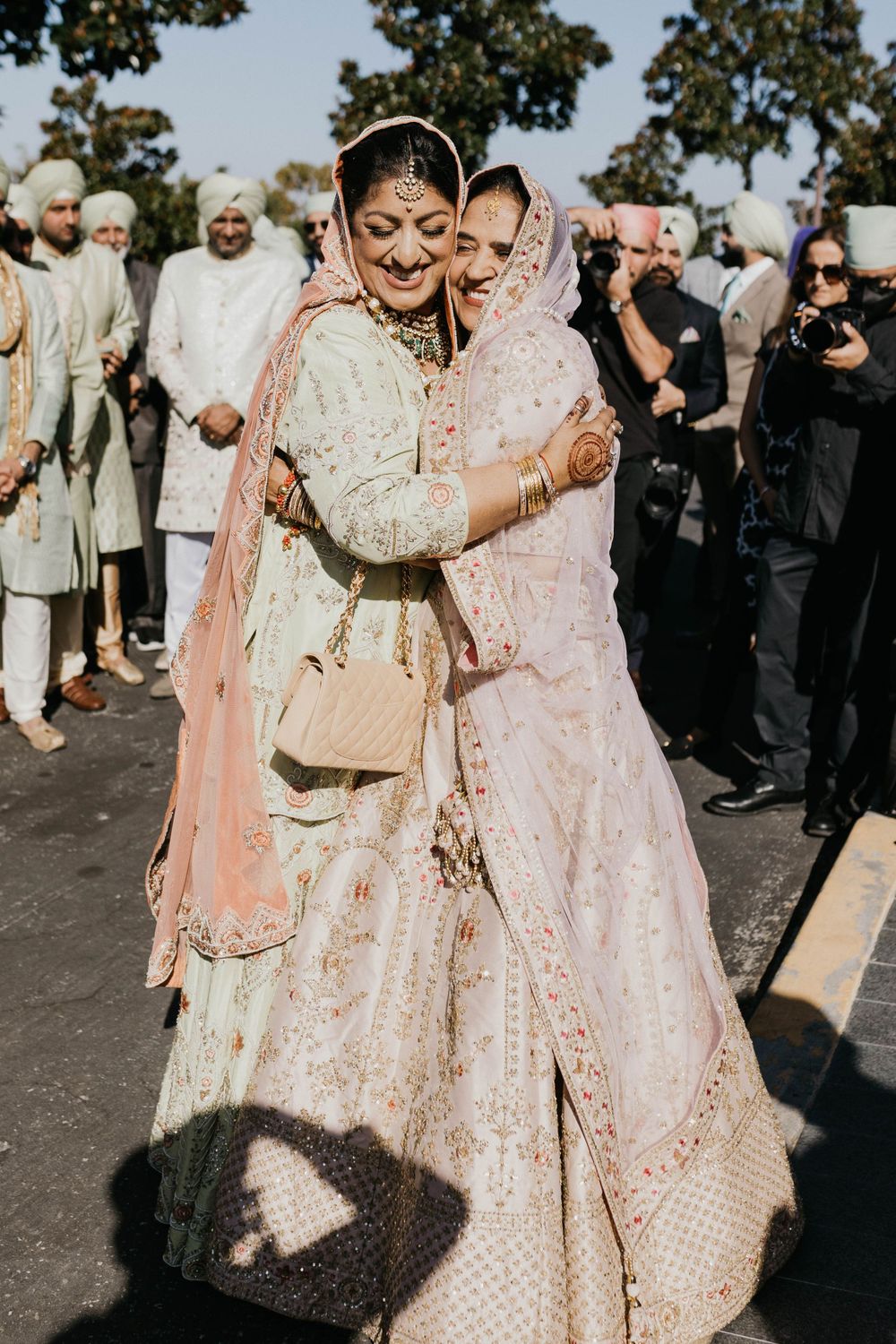 Joyful celebration at outdoor Indian wedding with guests in traditional attire.