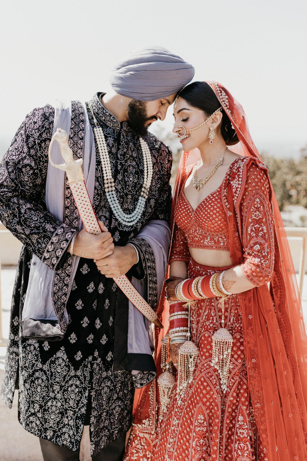 Romantic couple portrait in traditional Indian wedding attire with embroidered details.
