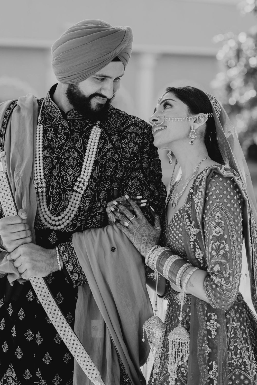 Black and white wedding photos showing intimate moments between a couple in traditional Indian attire.