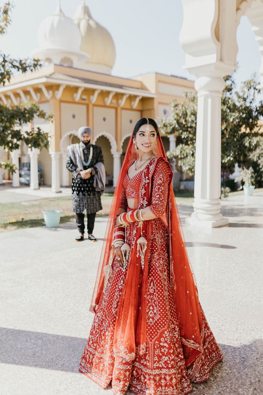 Wedding photos of a couple in traditional Indian attire posing in front of a white temple structure.