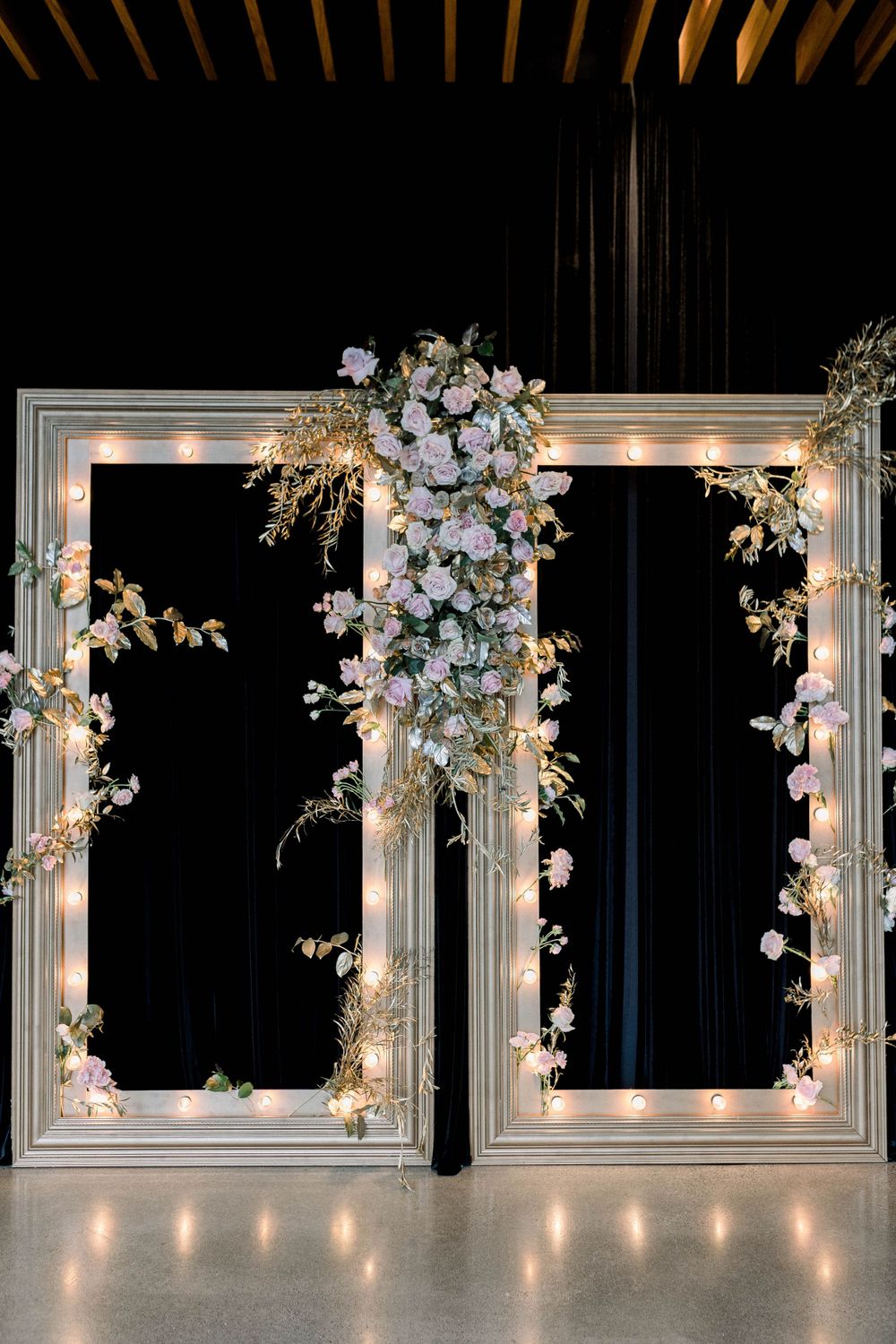 Elegant white floral wedding backdrop with illuminated frames and orchids.