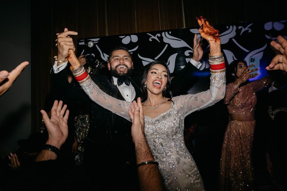 Festive crowd dancing with arms raised during an energetic indoor celebration.