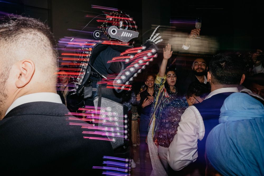 Dance party scene with colorful purple lighting and silhouettes of people.
