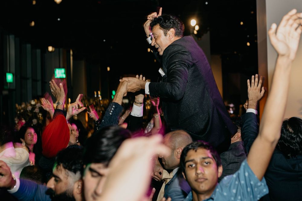 Energetic crowd at a dance party with raised hands and people dancing.