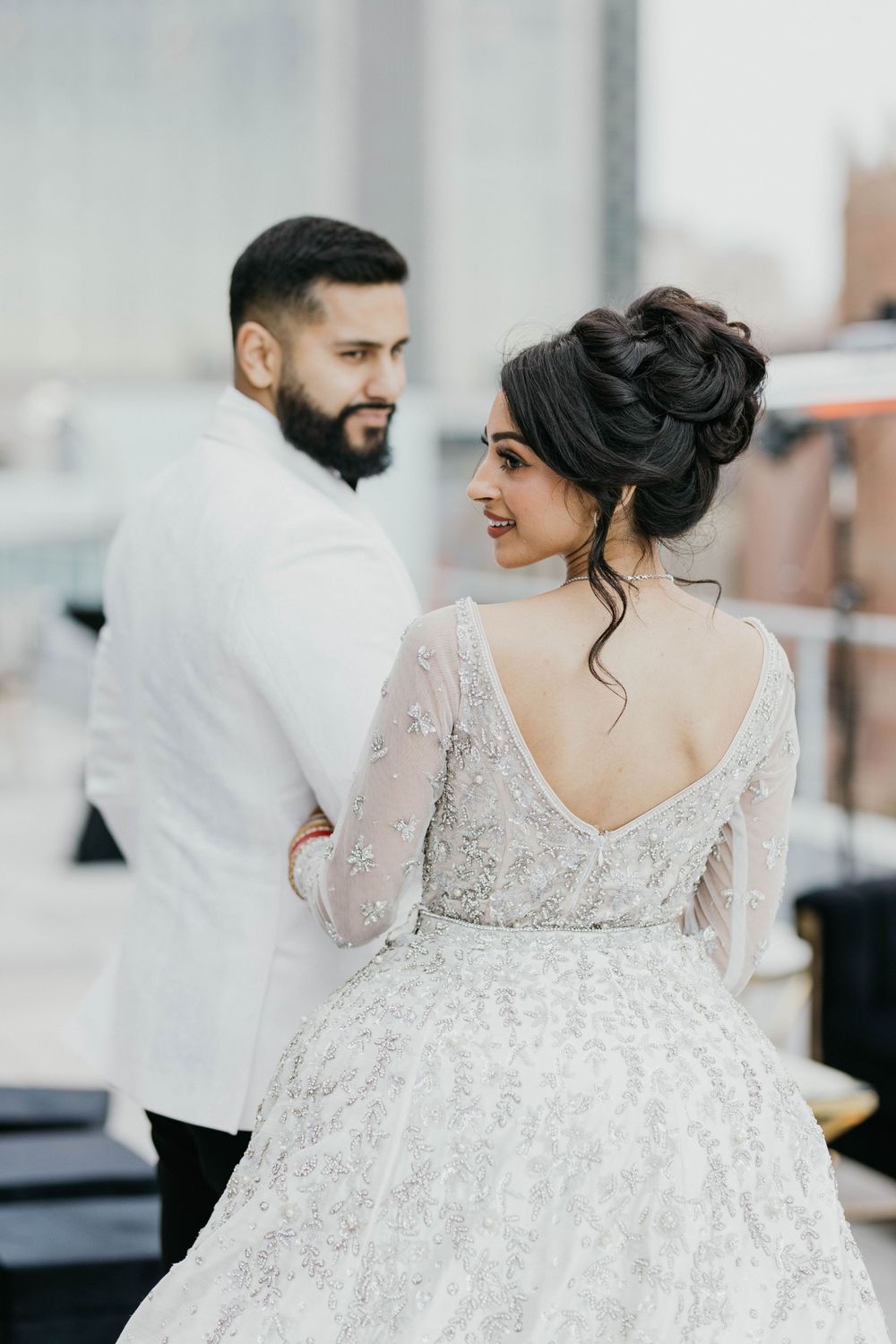 Wedding attire featuring detailed lace back dress and white tuxedo jacket.