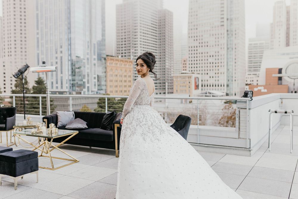 Elegant bridal gown on rooftop with city skyline backdrop.