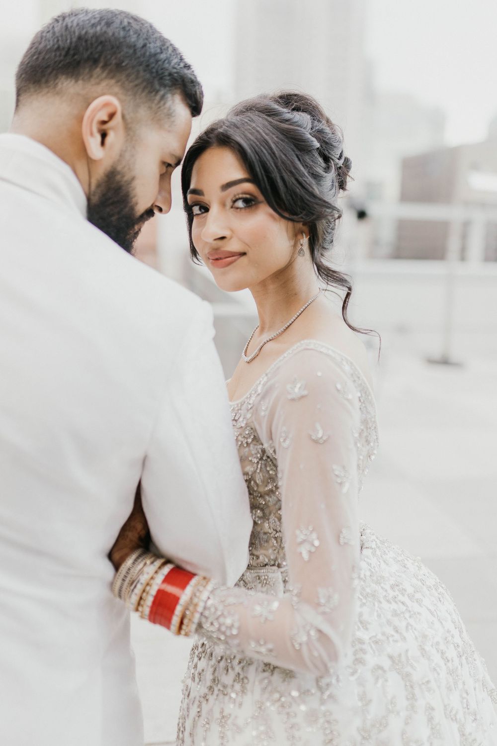 Intimate wedding portrait with delicate lace details and traditional red bangles.