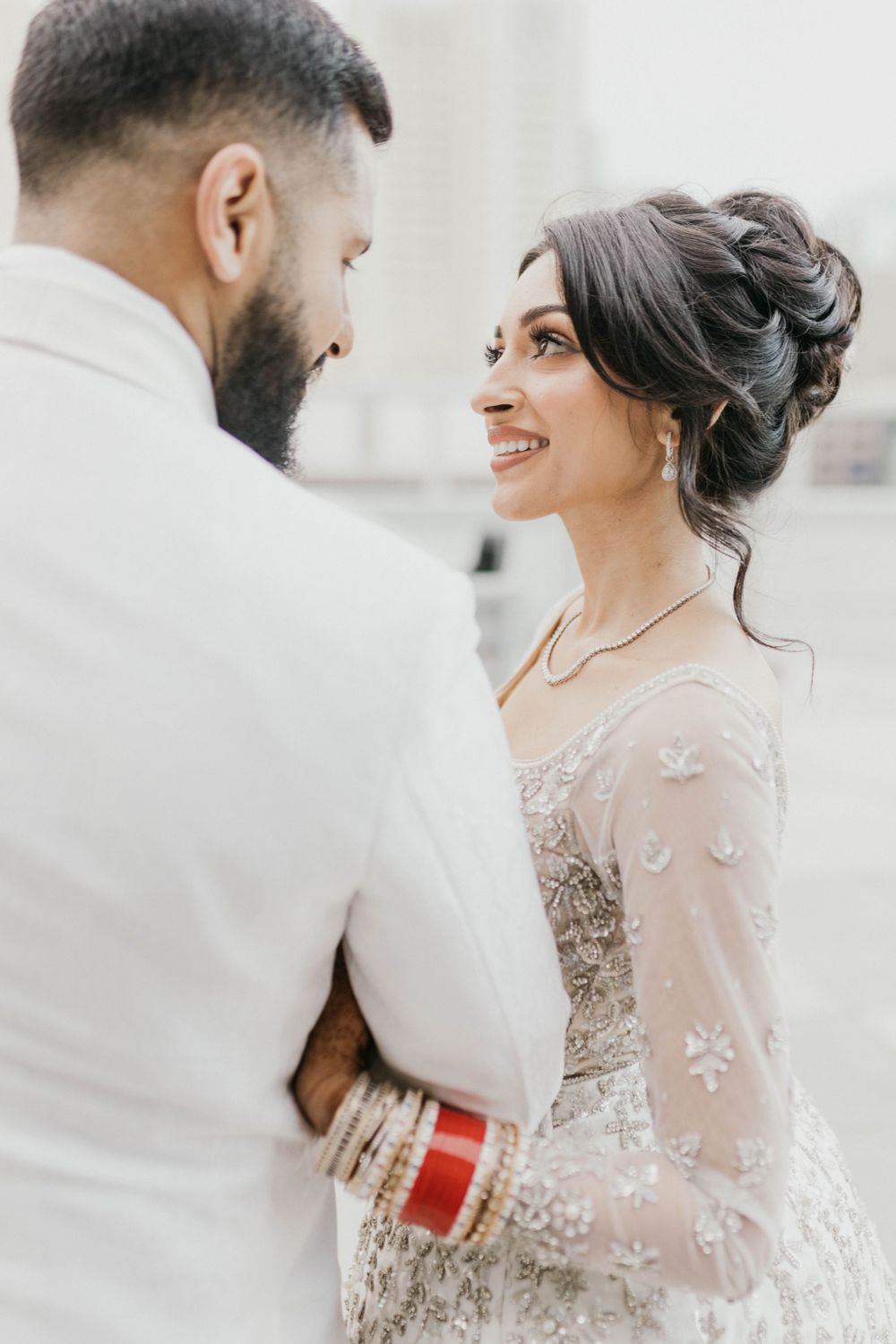 Romantic wedding couple sharing an intimate moment in elegant white and sheer attire.