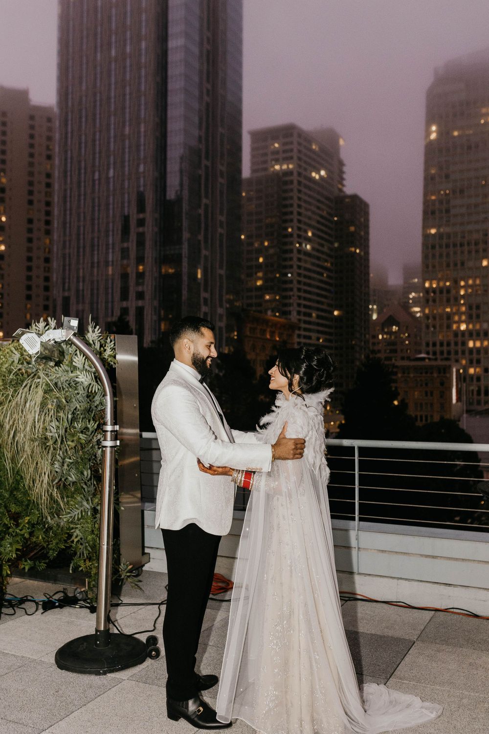 Evening rooftop wedding ceremony with city lights twinkling in the background.