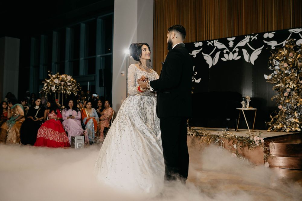 Elegant ballroom wedding reception with floral decor and dancing under soft lighting.