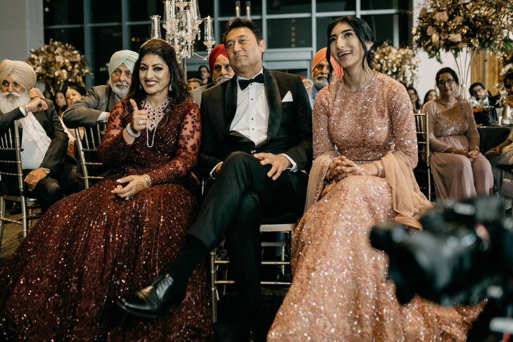 Wedding guests and decorative lights fill an elegant indoor reception venue.