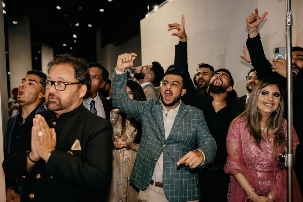 Guests dancing energetically at a wedding reception with dim lighting.