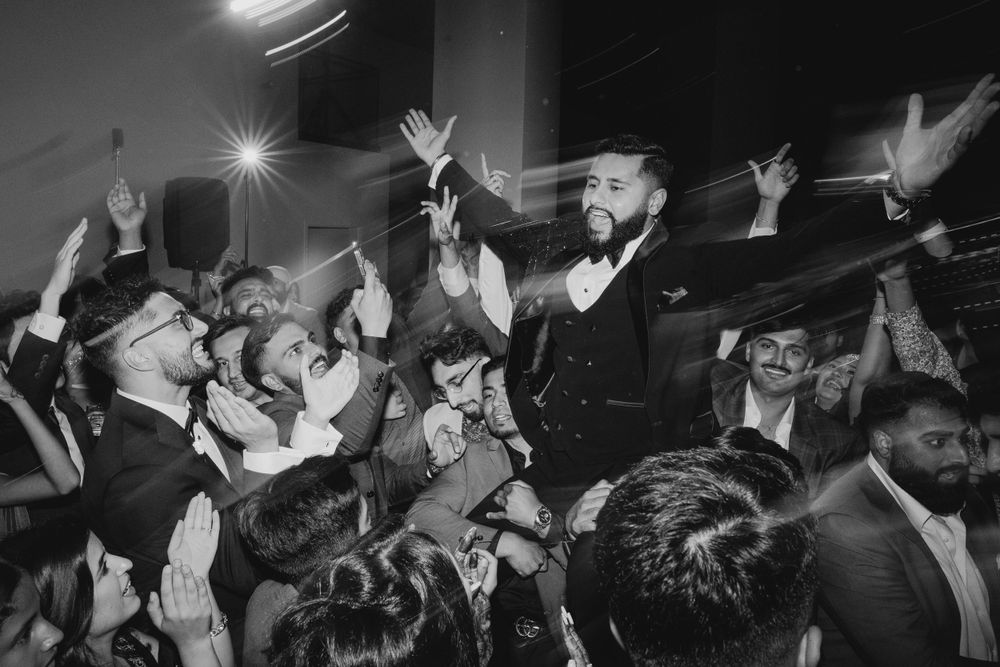 Black and white shot of guests raising their hands during a celebration dance.