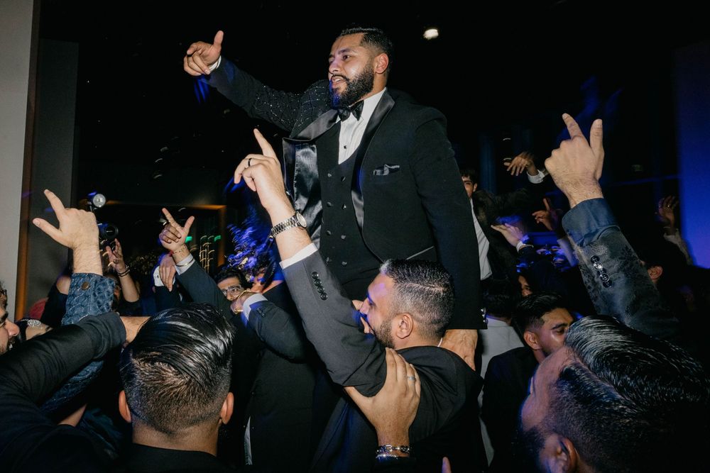 Party crowd with raised hands silhouetted against dark background during celebration.