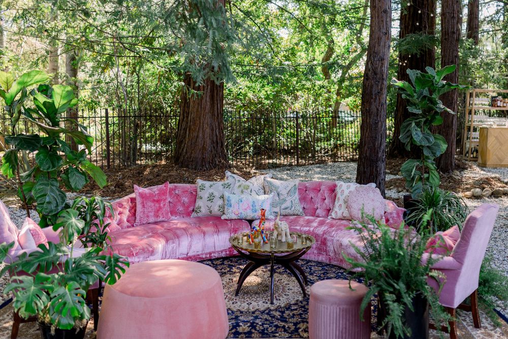 Pink tablescape settings arranged under lush green garden trees.
