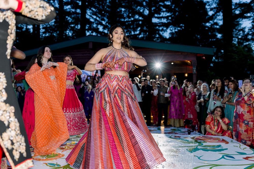 Wedding party dancing outdoors with colorful traditional South Asian dresses and decorations.