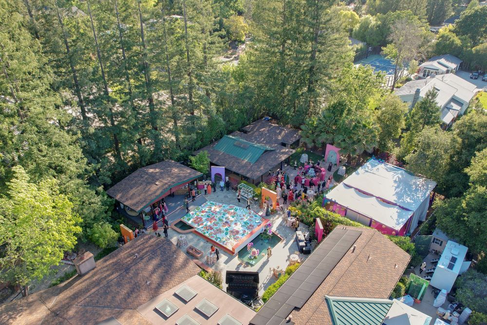 Aerial view of outdoor venue spaces with trees and buildings in a park-like setting.