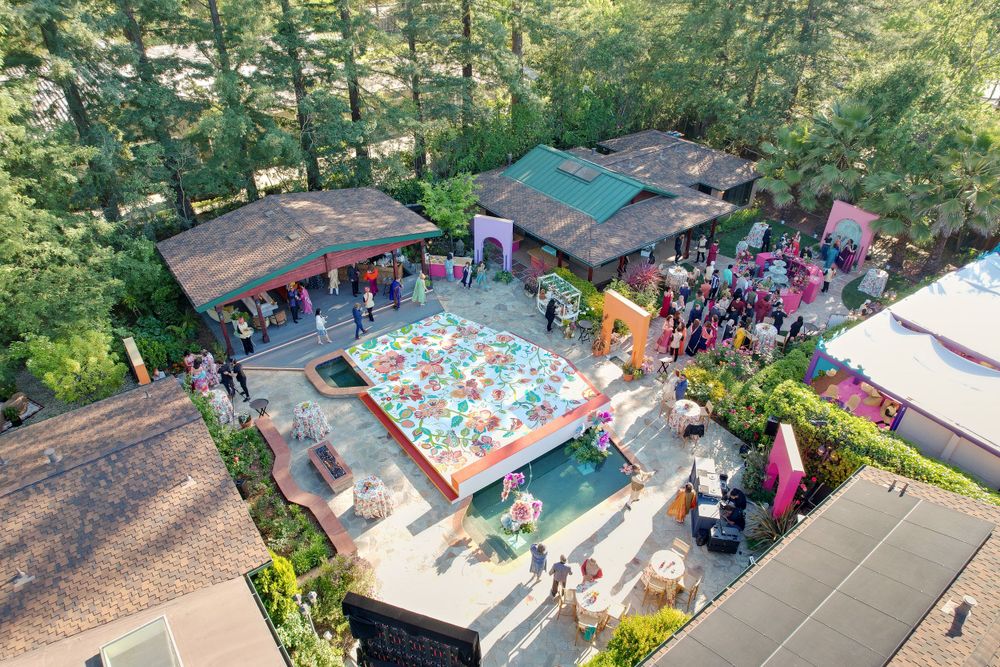 Overhead drone shot of swimming pools and outdoor facilities in a lush green setting.