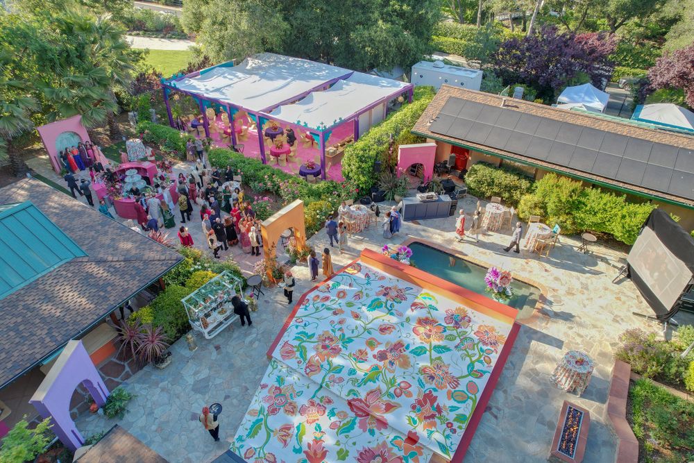 Bird's eye view of colorful outdoor pool and recreational areas surrounded by trees.