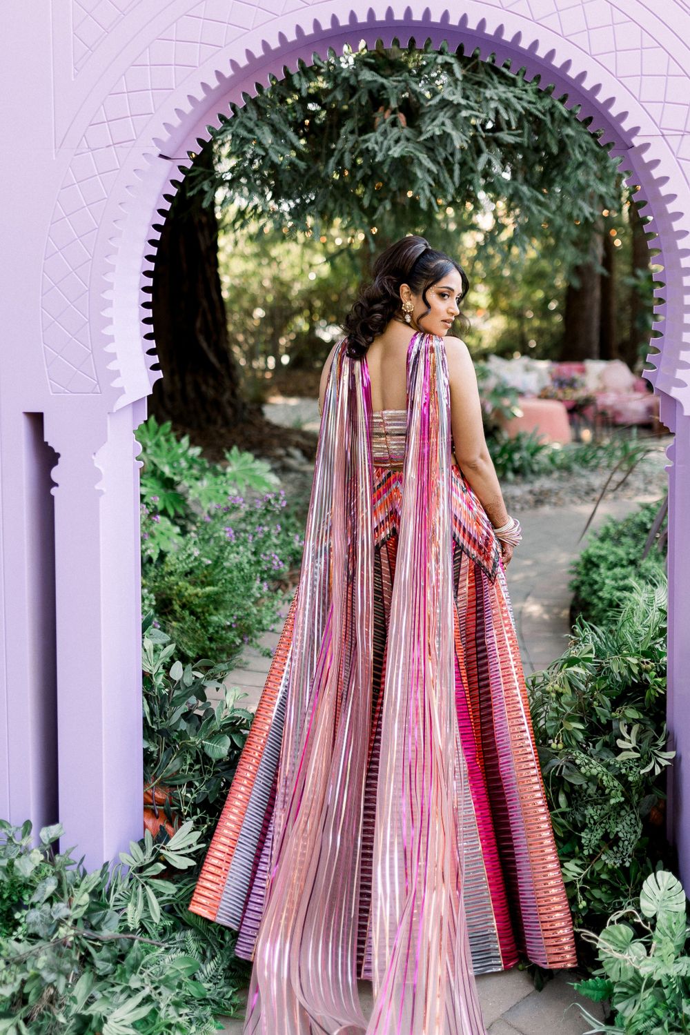 A flowing striped dress captured in movement through ornate white archways.